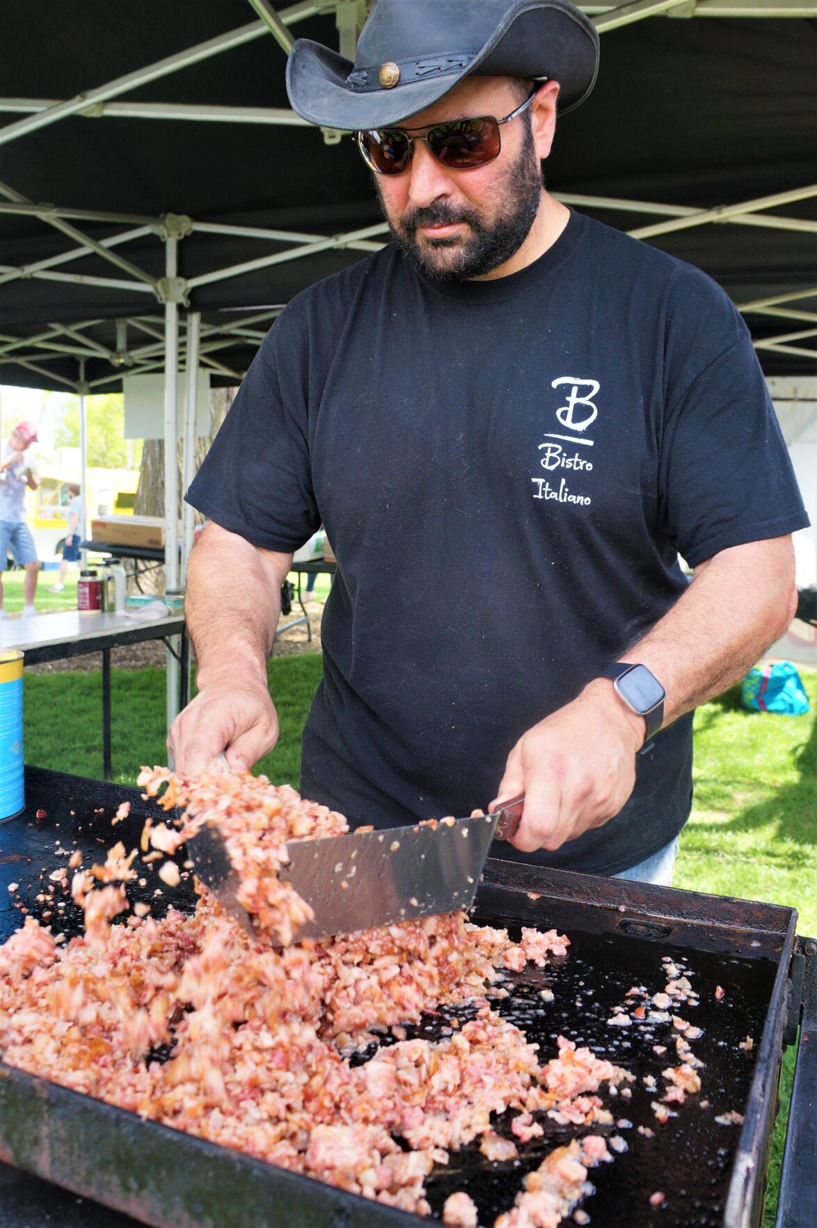 Bacon Fest vendor Peter Pucillo crisps chopped bacon on the griddle